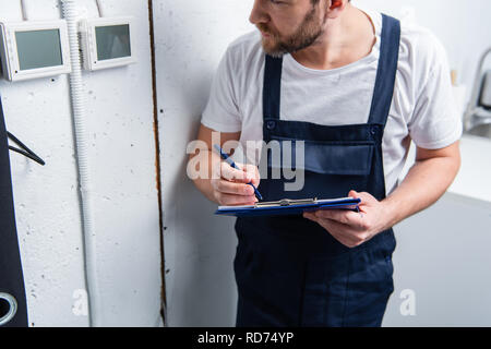 cropped image of adult electrician with clipboard checking electrical panel Stock Photo