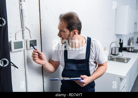 concentrated adult electrician with clipboard checking electrical panel Stock Photo