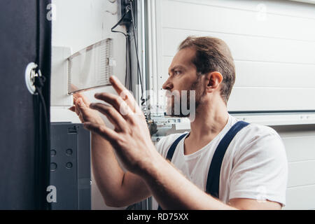concentrated male bearded handyman checking electrical box Stock Photo