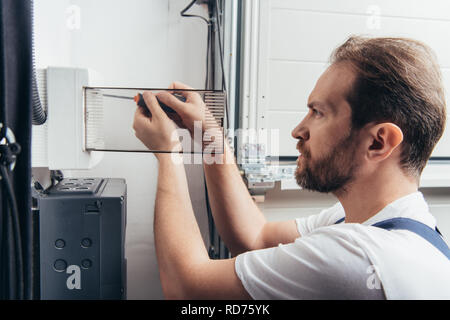 focused adult male electrician repairing electrical box by screwdriver Stock Photo