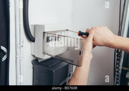 cropped image of male electrician repairing electrical box by screwdriver Stock Photo