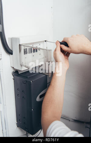 partial view of male electrician repairing electrical box by screwdriver Stock Photo