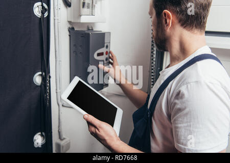 male bearded repairman with digital tablet checking electric box Stock Photo