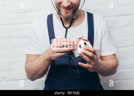 partial view of male handyman checking house figure by stethoscope, home inspection concept Stock Photo