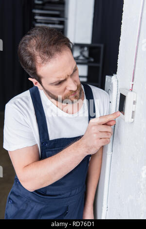 focused adult male handyman checking electrical panel Stock Photo