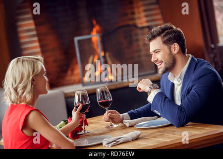 Young couple on date in restaurant sitting drinking wine talking joyful Stock Photo