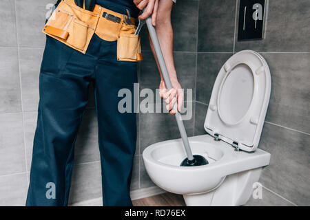 partial view of male plumber using plunger and cleaning toilet in bathroom Stock Photo