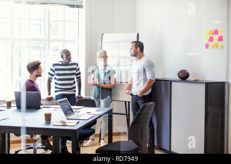 Diverse group of focused designers discussing a project together inside of an office after a meeting Stock Photo