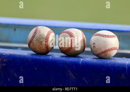 Three baseballs sitting on the dugout fence Stock Photo