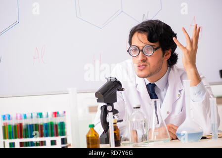 Young funny chemist in front of white board Stock Photo