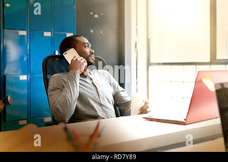 Attractive young black man working in modern office space Stock Photo