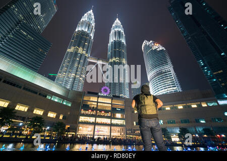 Young Asian man traveler wearing casual with backpack bag enjoy amazing weekends. Looking away to  building in Kuala Lumpur, Malaysia. Asia Stock Photo