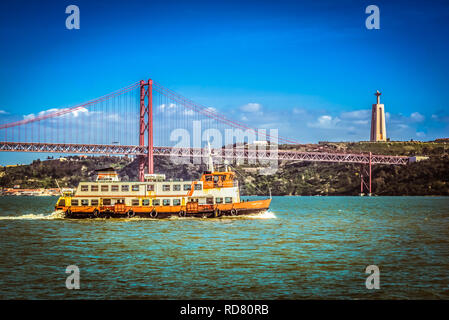 Lisbon, Portugal. A former ferry boat (now touristic cruiser) on the Targus in front of famous bridge Ponte 25 de Abril and Cristo Rei monument. Stock Photo