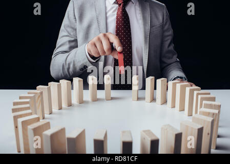 partial view of businessman picking wooden red brick from circle of blocks on desk isolated on black Stock Photo