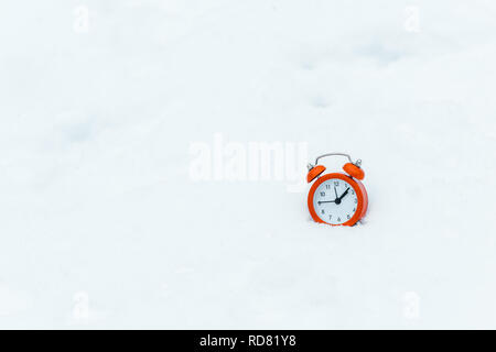 isolated in white of alarm clock standing on white snow Stock Photo