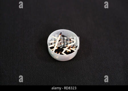 Burned matchstick in the small pot. Isolated on the black background. Stock Photo