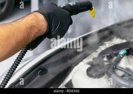 Car detailing. Car washing cleaning engine. Cleaning car engine using hot steam. Hot steam engine washing. Soft lighting. Car wash station worker clea Stock Photo