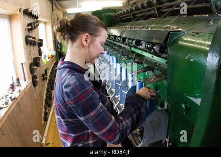 Highly skilled Swedish woman using restored wool and textile machines from 19th century to run a production line of sustainably produced wool and textile products . Stock Photo