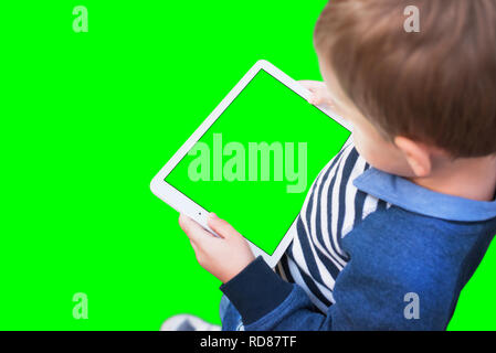 Boy play game on white tablet. Isolated screen and background in green, chroma key. Stock Photo