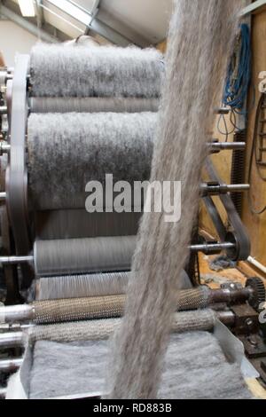 Wool thread being spun from raw wool product , part of process to create woll knitwear products in Woolen mill Stock Photo