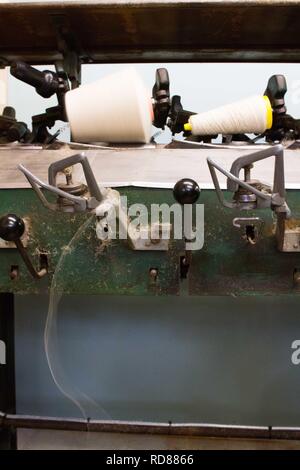 Highly skilled Swedish woman using restored wool and textile machines from 19th century to run a production line of sustainably produced wool and textile products . Stock Photo