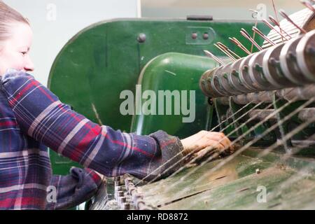 Highly skilled Swedish woman using restored wool and textile machines from 19th century to run a production line of sustainably produced wool and textile products . Stock Photo