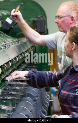 Highly skilled Swedish woman using restored wool and textile machines from 19th century to run a production line of sustainably produced wool and textile products . Stock Photo