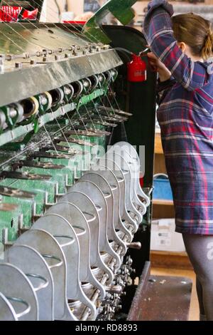 Highly skilled Swedish woman using restored wool and textile machines from 19th century to run a production line of sustainably produced wool and textile products . Stock Photo