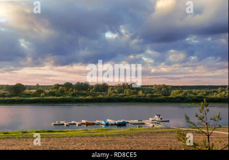 A small river with a pier for catamarans and a sandy beach on the shore on a clear Sunny day. Stock Photo
