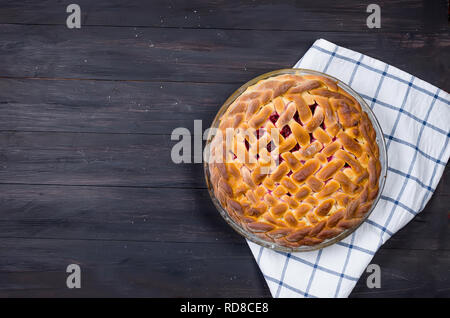 Delicious Homemade cherry Pie in a glass round form  on the dark old wooden table. Making cherry Pie Series, Stock Photo