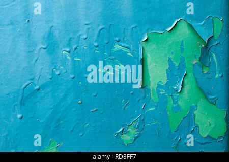 Peeling blue paint over green paint on vertical metal surface. Stock Photo