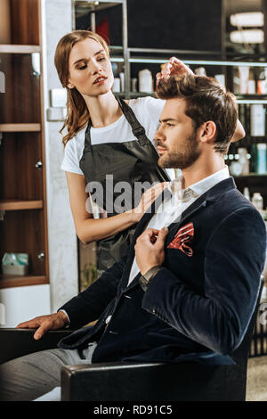 young hairdresser doing hairstyle to handsome man in beauty salon Stock Photo