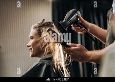 cropped shot of hairdresser drying hair to smiling girl in beauty salon Stock Photo