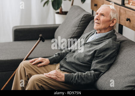 thoughtful pensioner with grey hair sitting on sofa Stock Photo