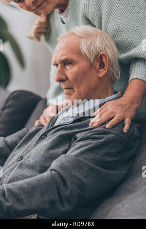 cropped view of retired wife embrace senior husband shoulders at home