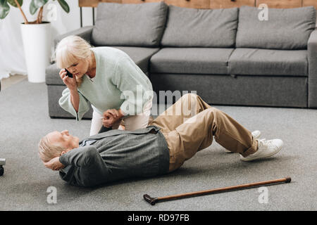 senior woman holding hand of dying old man with walking stick Stock Photo