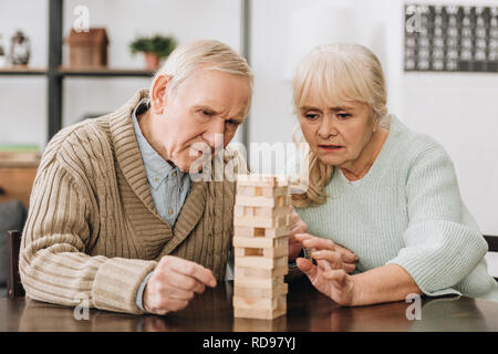 retired couple playing jenga game on table Stock Photo