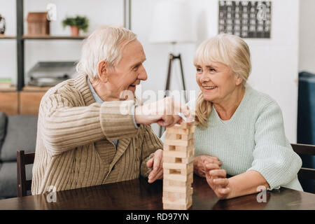 smiling pensioners playing jenga game on table Stock Photo