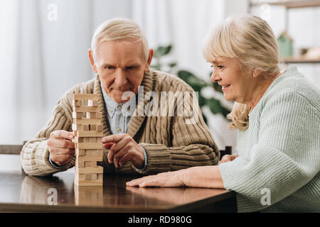 retired husband and wife playing jenga game on table Stock Photo