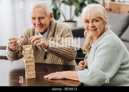 happy pensioners playing jenga game on table Stock Photo