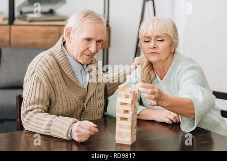 retired couple playing jenga game on table at home Stock Photo