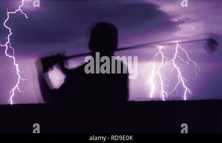 A silhouette of a golfer at the end of his stroke while lightning flashes in the distance during a monsoon in Phoenix, Arizona. Stock Photo