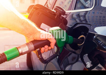 Refueling the car at a gas station fuel pump. Man driver hand refilling and pumping gasoline oil the car with fuel at he refuel station. Car refueling Stock Photo