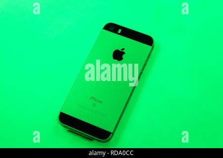 Paris, France - Apr 21, 2016: Newest Apple Computers iPhone SE smartphone after unboxing on green vivid right background featuring Stock Photo