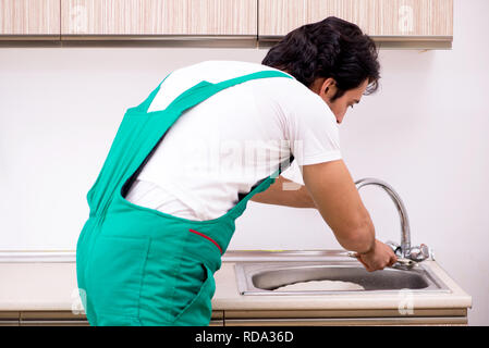 Young plumber repairing tap at kitchen Stock Photo