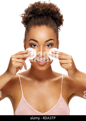 Beautiful girl holding cotton pads near face. Photo of african american girl with flawless skin isolated on white background. Skin care and beauty con Stock Photo