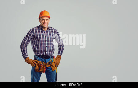 Repairman in special clothes with tools on a gray background. Stock Photo