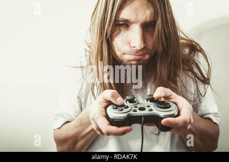 Lifestyle of young people. Student man spending time on playing games videogames console playstation. Long haired guy focus on gaming. Stock Photo
