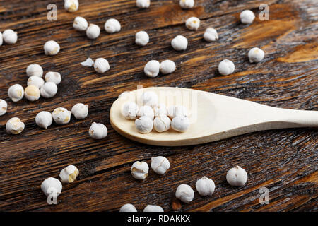 raw chickpeas in a spoon and scattered on a wooden background, organic food, vegetarian cuisine Stock Photo