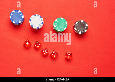 Flat lay concept: image of several red dice and chips on red background with copy space. Stock Photo